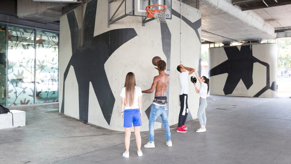Vier Jugendliche stehen vor einem Basketball-Korb.