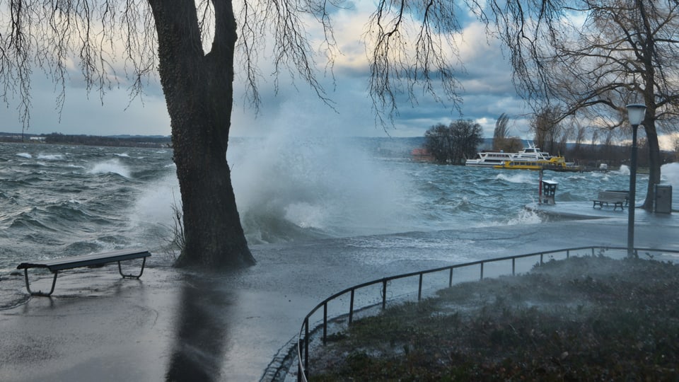 Wellen des Zugersees schlagen über die Uferpromenade.