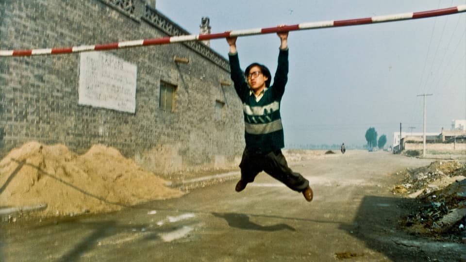 Filmstill aus Jia Zhang-kes erstem Film «Pickpocket»: Ein Chinese hält sich mit beiden Händen an einer Barriere fest.