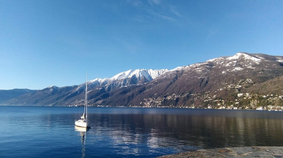 Der wolkenlose Lago Maggiore mit der verschneiten Kuppe des Monte Gridone