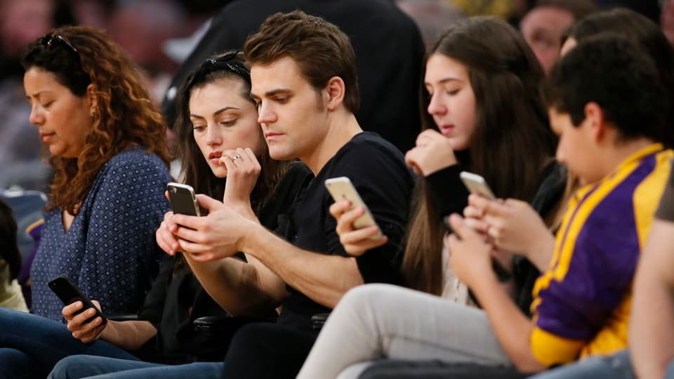 Junge Leute gucken auf ihr Smartphone. 