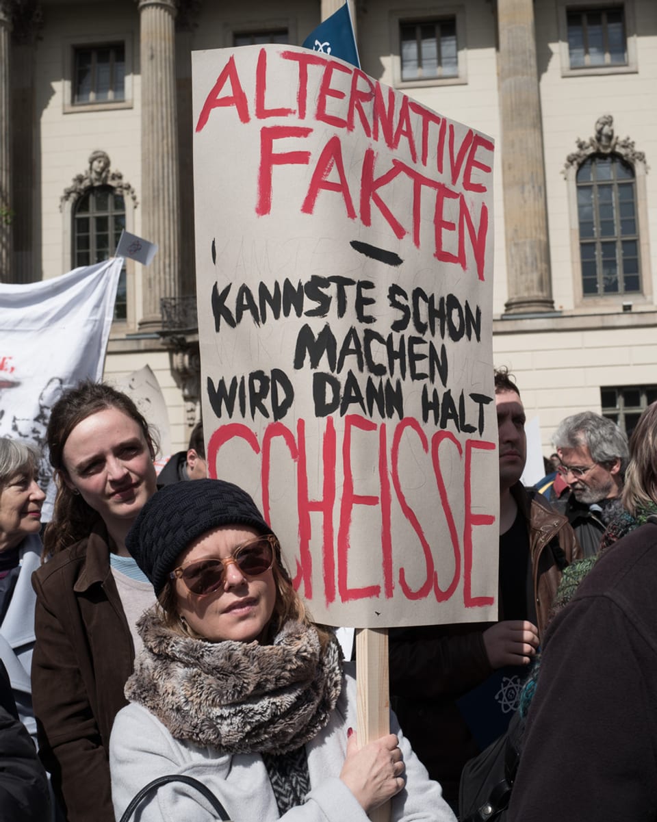 Eine Frau hält ein Plakat, auf dem steht: «Alternative Fakten - kannste schon machen, wird dann halt scheisse.»»