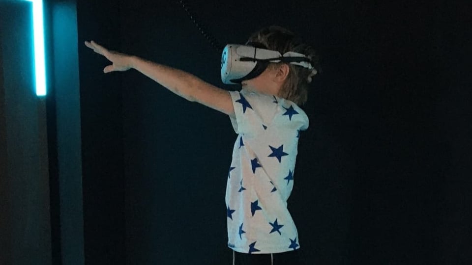 Ein Kind trägt eine VR-Brille und streckt die Hand aus