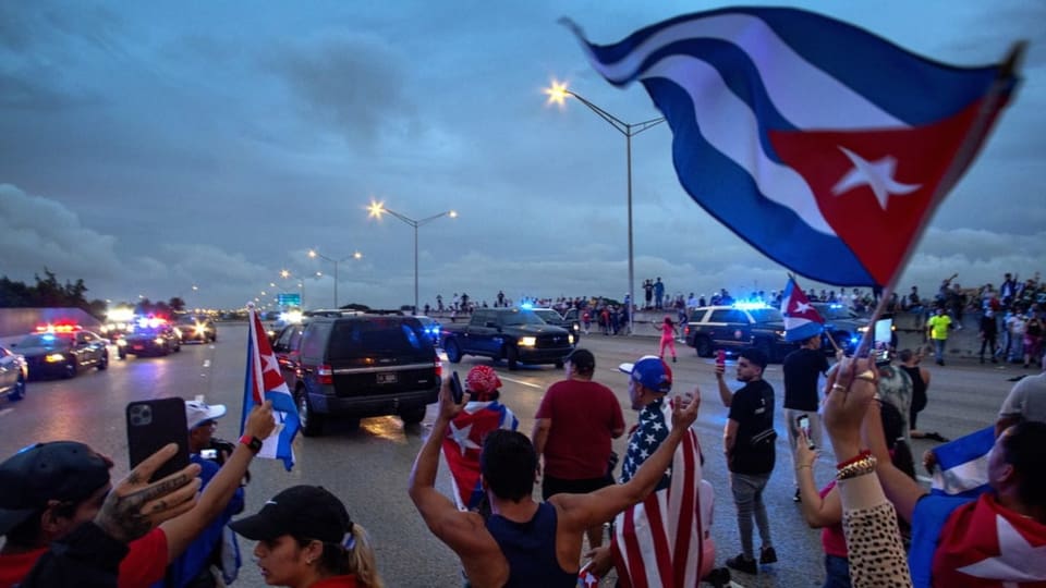 Menschen mit Kubafahnen blockieren eine mehrspurige Strasse.