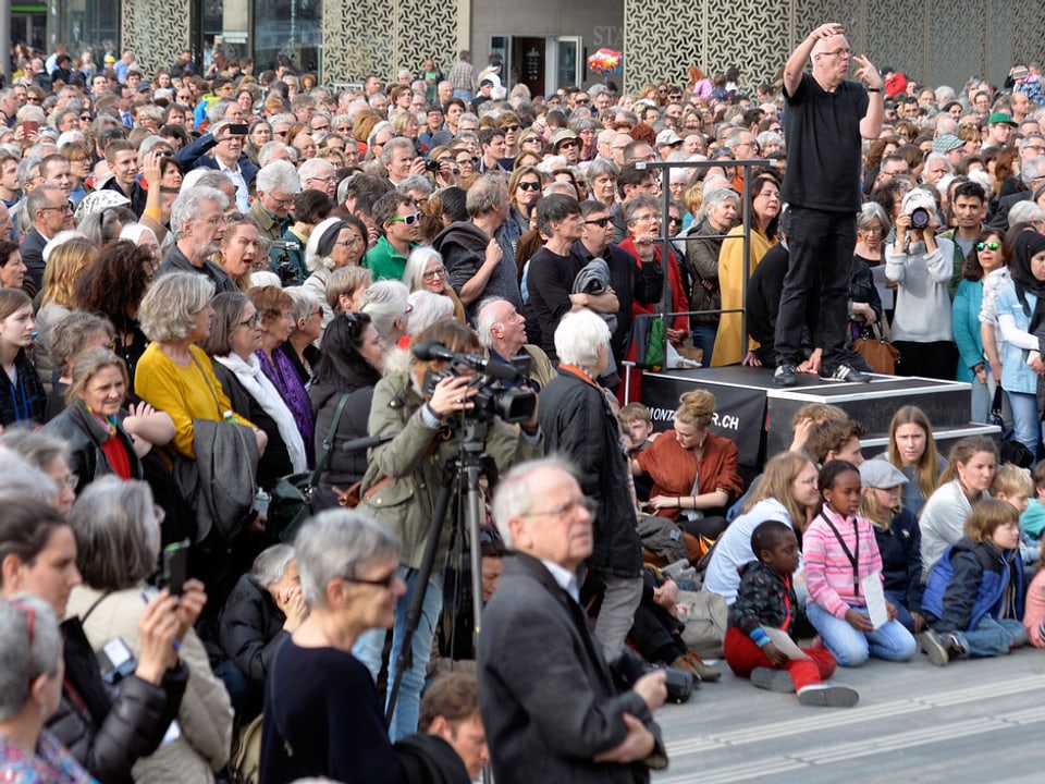 Christoph Homberger dirigiert umgeben von einer Zuschauermenge.
