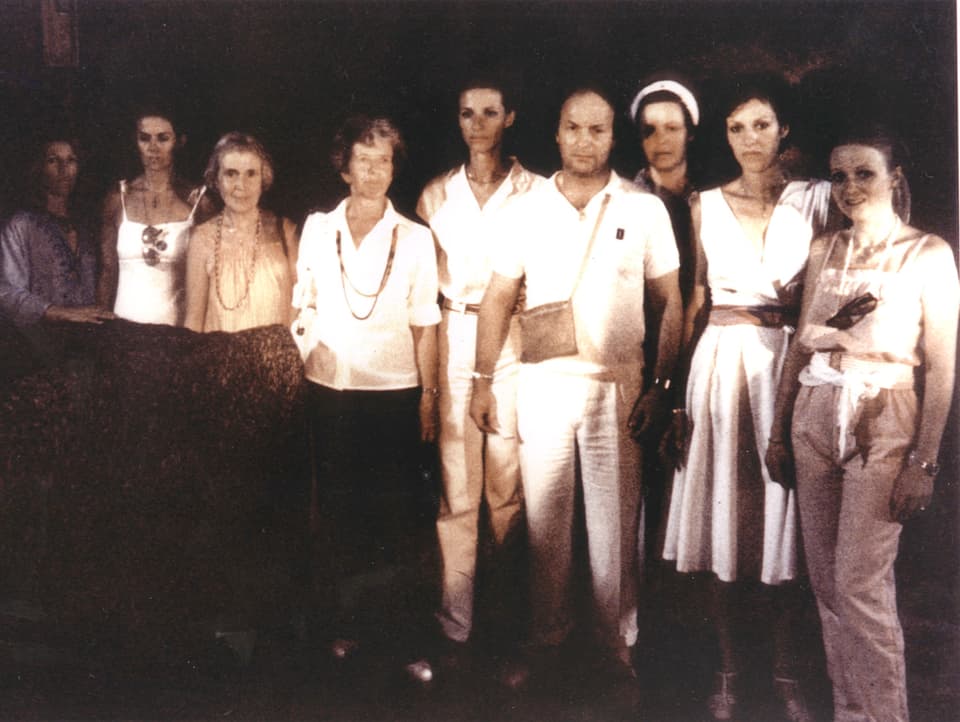 Neun Personen in heller Kleidung posieren für ein Foto