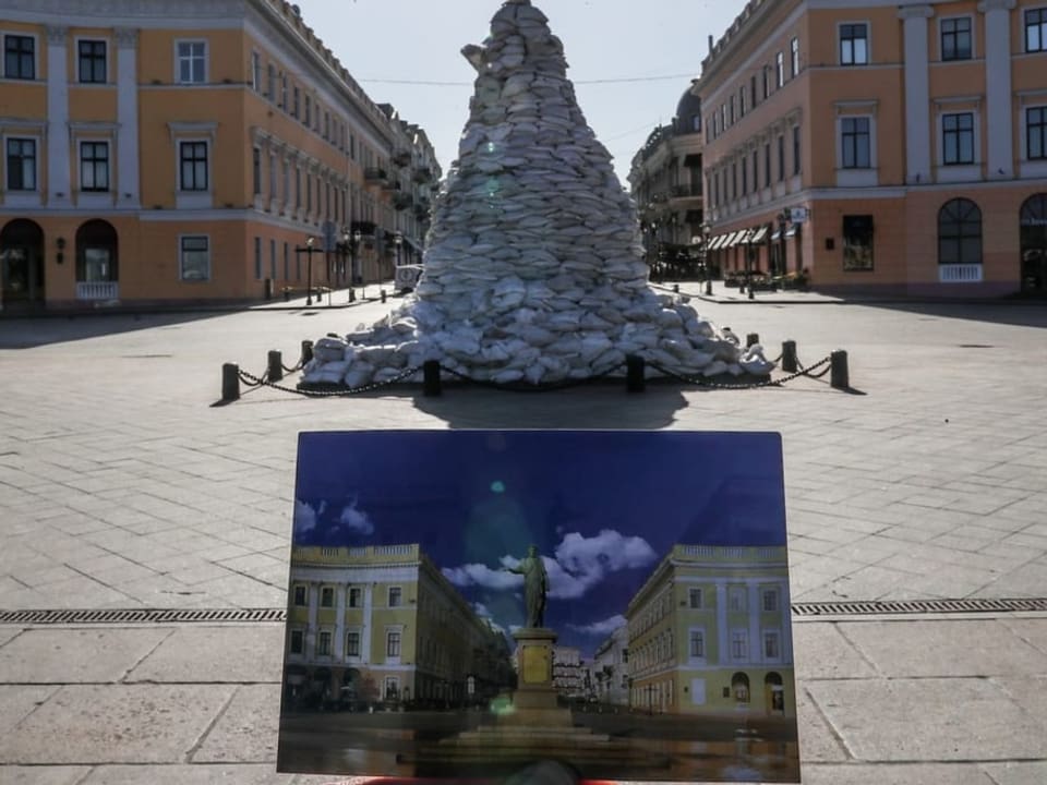 Denkmal mit Sandsäcken, Postkarte im Vordergrund