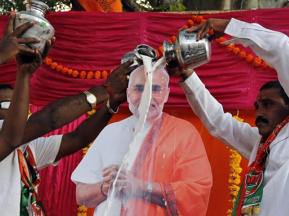 Anhänger giessen Milch über ein Foto von Narendra Modi.