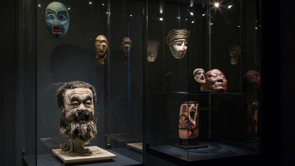 Vitrine mit Masken und einem dreidimensionalen Kopf des Künstlers Ai Weiwei.