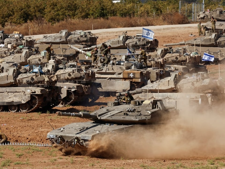 Militärfahrzeuge und Panzer mit Flaggen auf staubigem Gelände