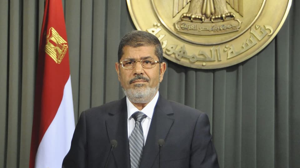 Präsident Mursi hält eine Rede – im Hintergrund die ägyptische Flagge.
