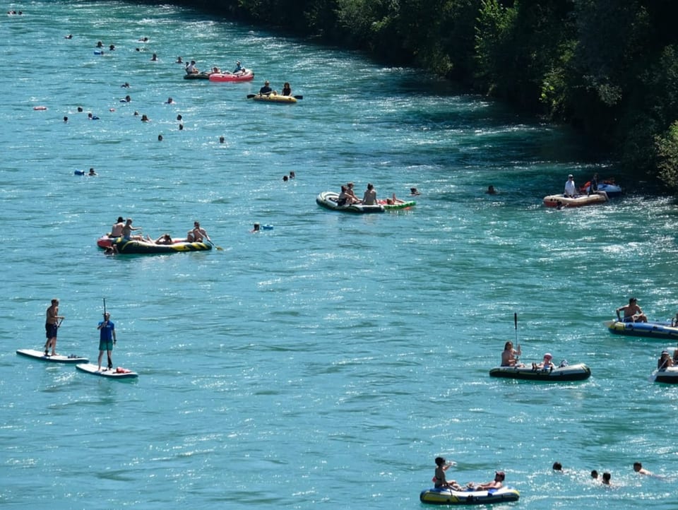 SUP'ler und Leute in Booten in einem Fluss