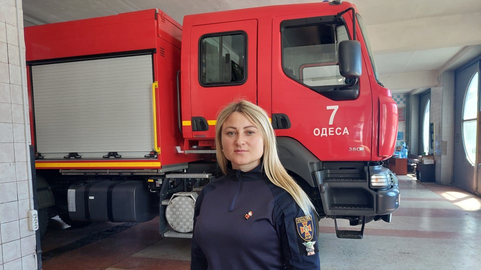 Woman in front of red fire truck in garage.