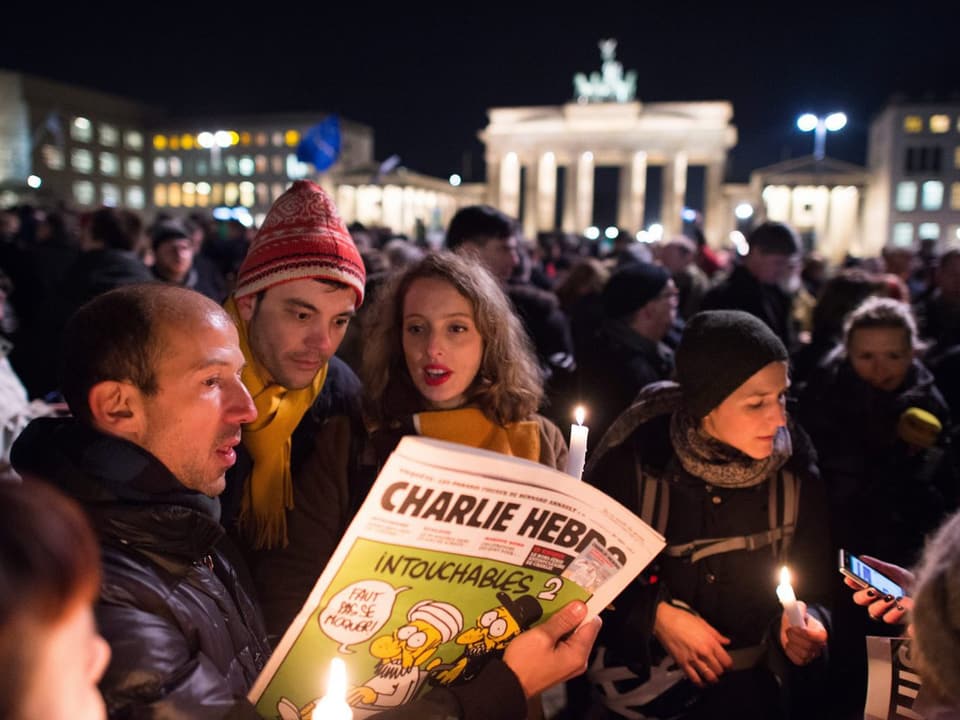 Ein Mann hält vor dem Brandenburger Tor eine Charlie-Ausgabe in den Händen.
