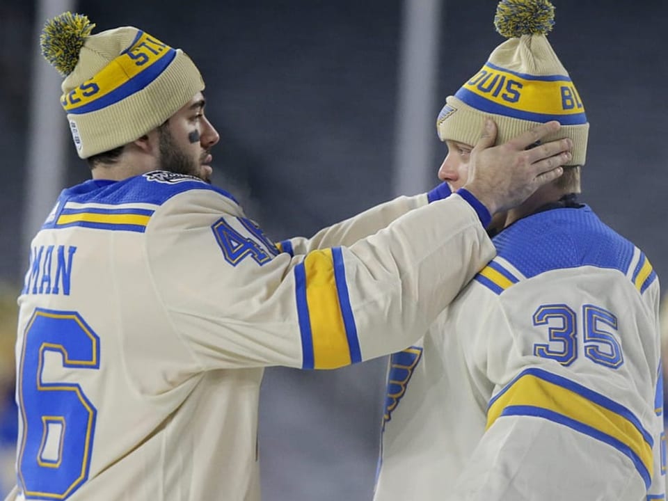 Zwei Spieler der St. Louis Blues setzen sich eine Mütze auf.