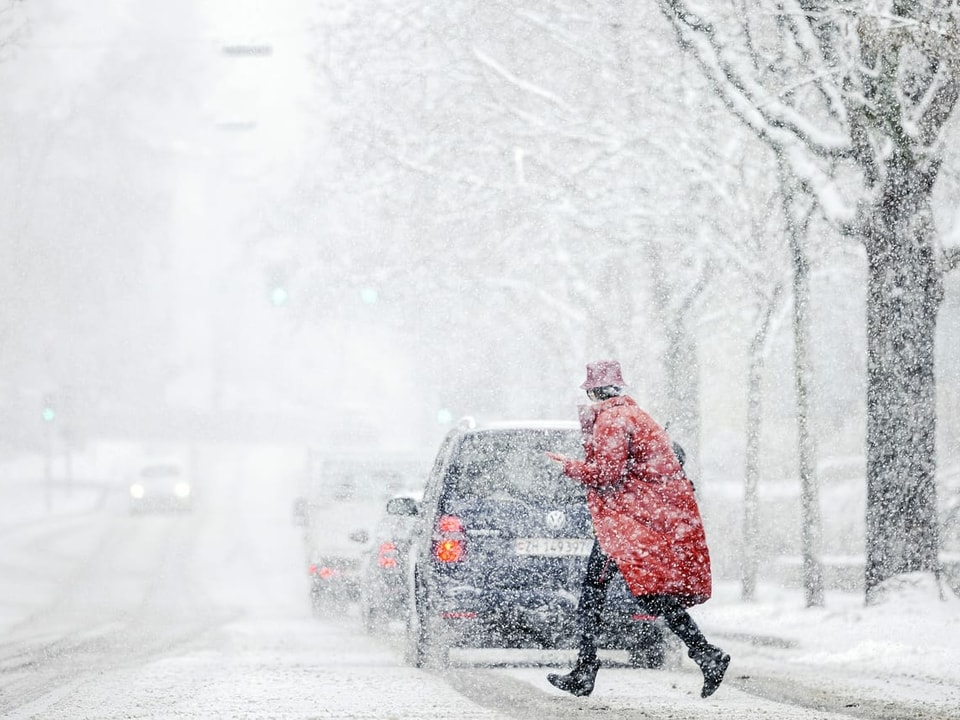 Person rennt im Schneegestöber über die Strasse.