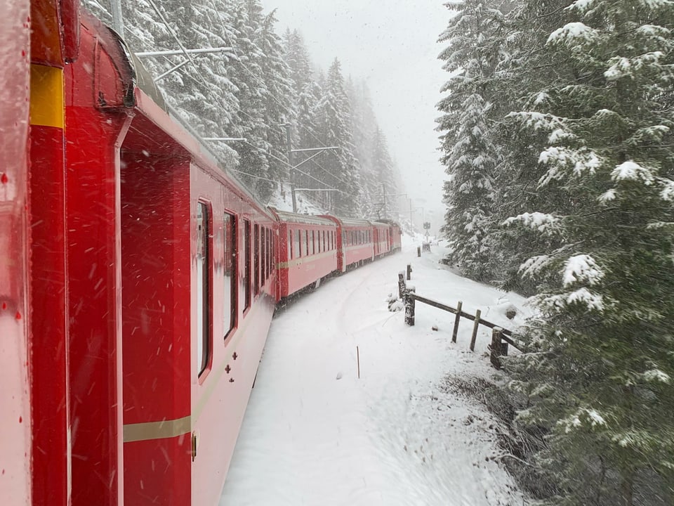 Rhätische Bahn fährt durch verschneite Landschaft.