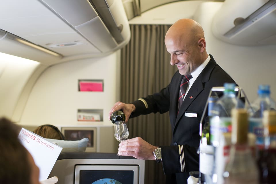 Flugbegleiter schenkt ein Glas Wein ein