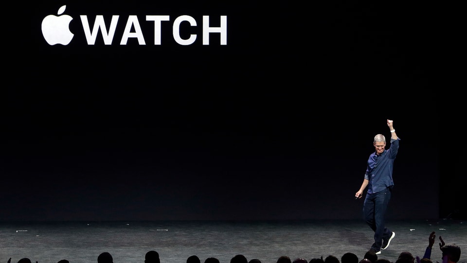 Vor dem Apple Watch Schriftzug hebt Tim Cook den Arm.