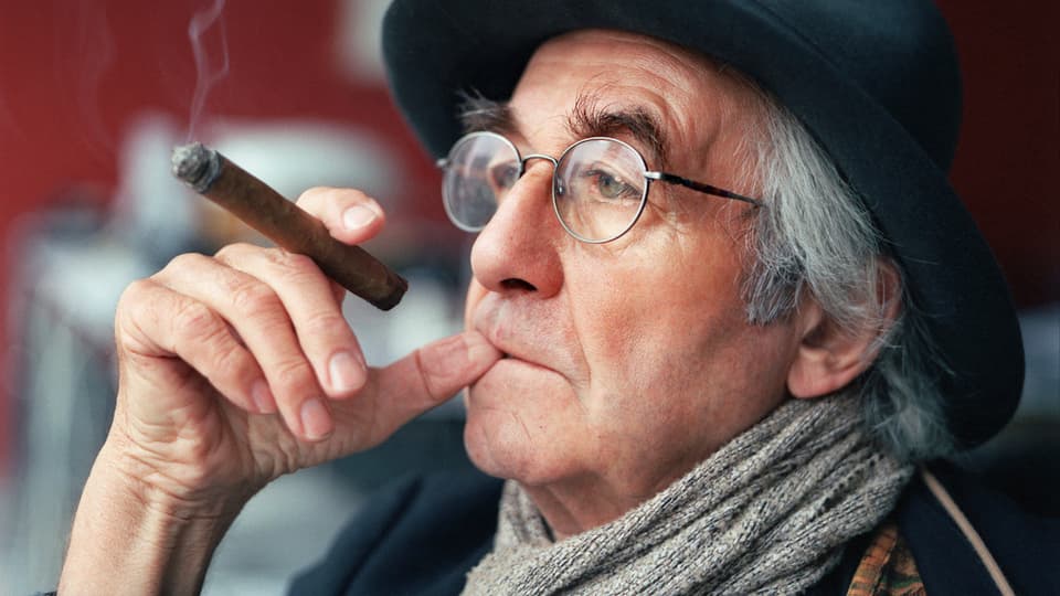 Nahaufnahme von René Burri, der eine Zigarre raucht.