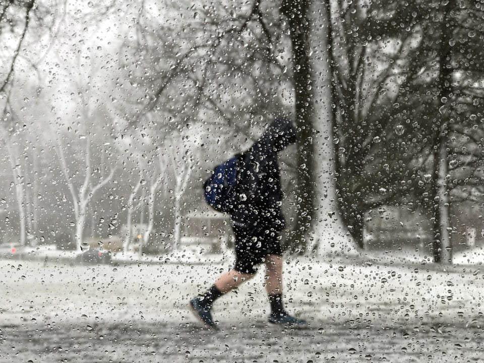 Eine Person schreitet durch Schneetreiben.