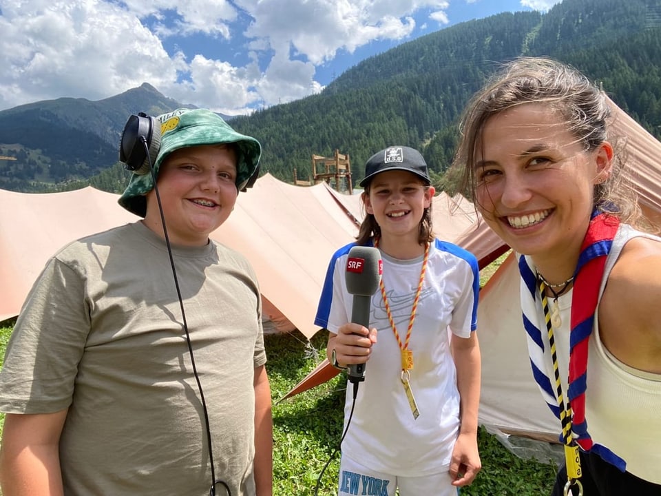 zwei Kinder und eine Frau machen ein Selfie vor dem Zelt