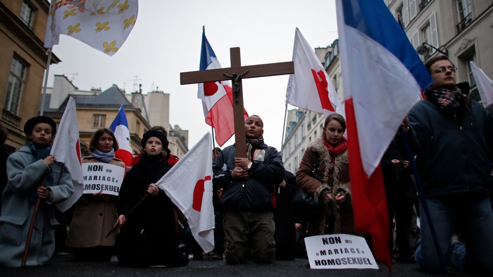 Demonstranten - darunter Kinder - protestieren mit Christus-Kreuz und Fahnen.