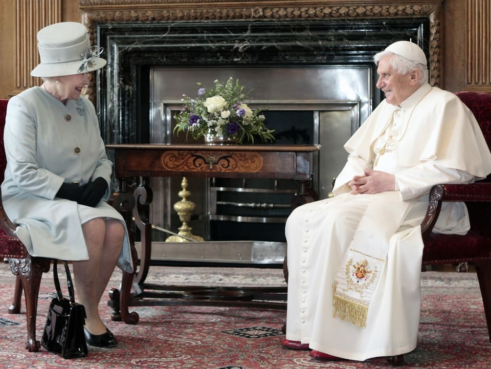 Die Königin und der Papst sitzen sich gegenüber.