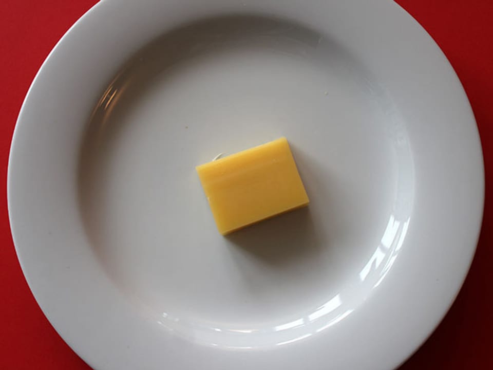 Stück Emmentaler-Käse auf einem Teller.
