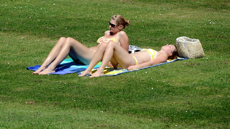 Zwei Frauen im Bikini sonnen sich auf der Wiese (Symbolbild)