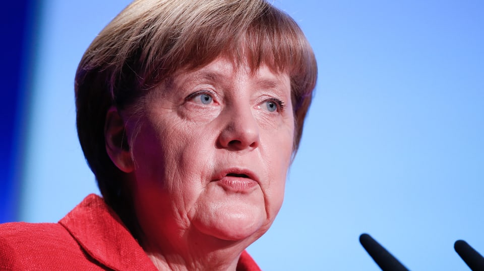 Angela Merkel in rotem Kleid in Grossaunfahme vor Mikrofonen