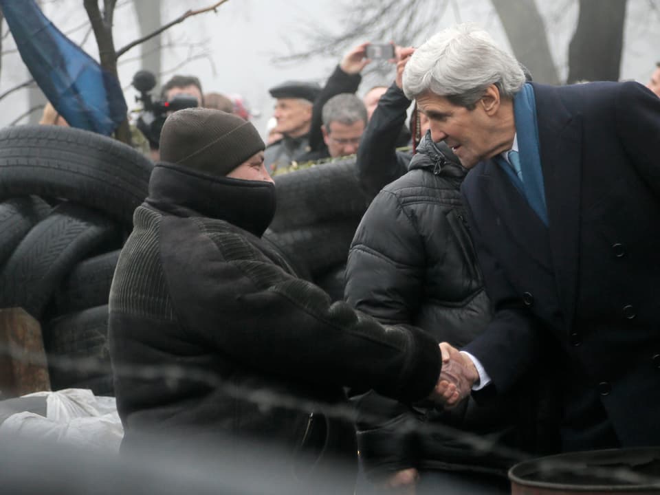 US-Aussenminister Kerry schüttelt in Kiew die Hand einer Demonstrantin.
