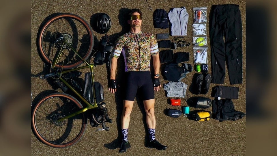 Tobias Müller liegt neben dem ausgebreiteten Gepäck und dem Fahrrad.