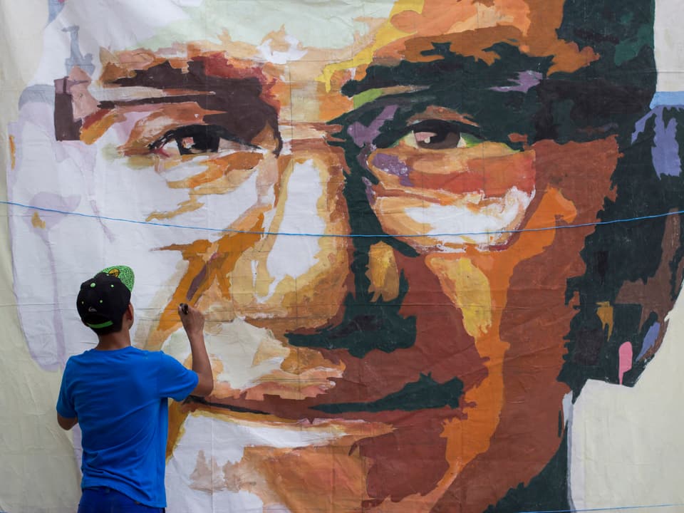 Ein junger Mann malt ein Porträt des verstorbenen Erzbischofs Oscar Romero