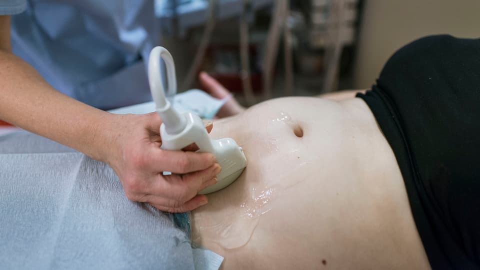 Ultraschallgerät fährt über Bauch einer Schwangeren.