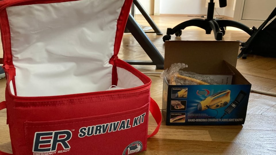 Eine rotes Survivaltasche und eine Kartonschachtel, worin der knallgelbe Apparat verpackt liegt.
