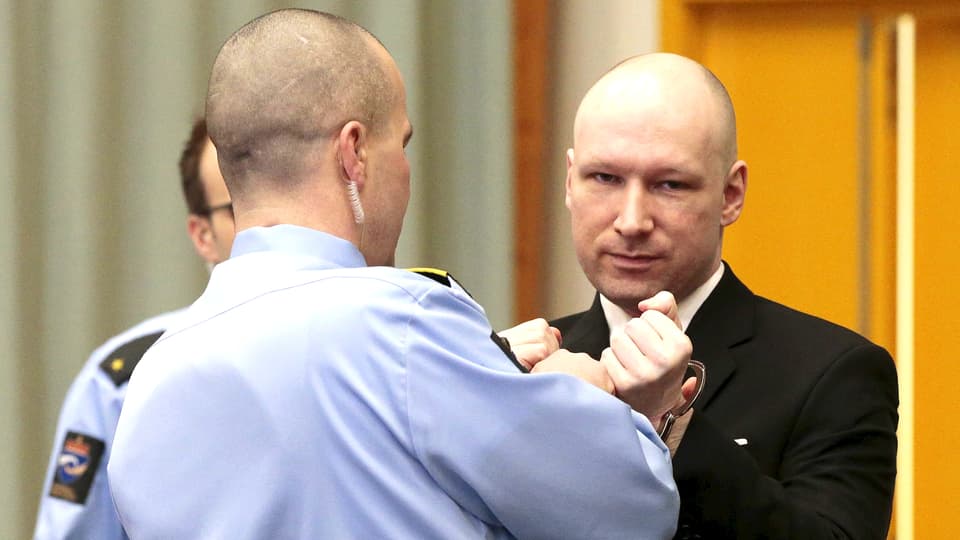 Dem Attentäter Anders Behring Breivik werden im Gerichtssaal im norwegischen Skien von einem Sicherheitsbeamten die Handfesseln abgenommen.