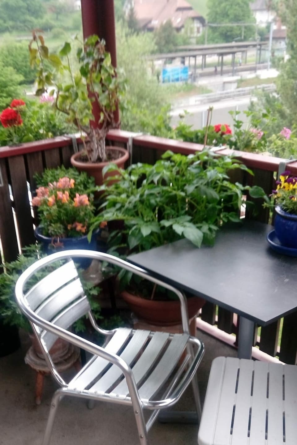 Balkon mit Stühlen und Tisch aus Alluminium mit Blick auf Strasse. 