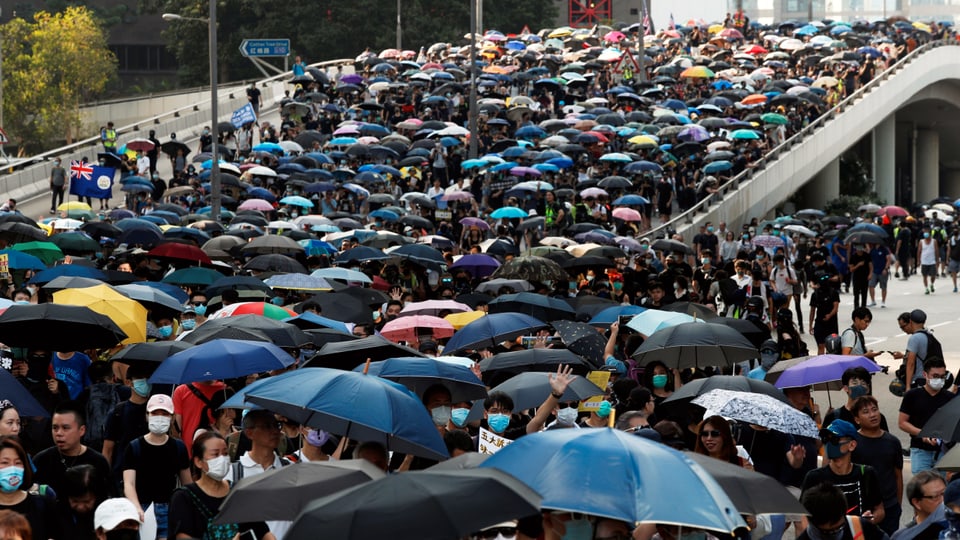 Demonstranten mit Regenschirmen marschieren durch die Strassen Hongkongs. 