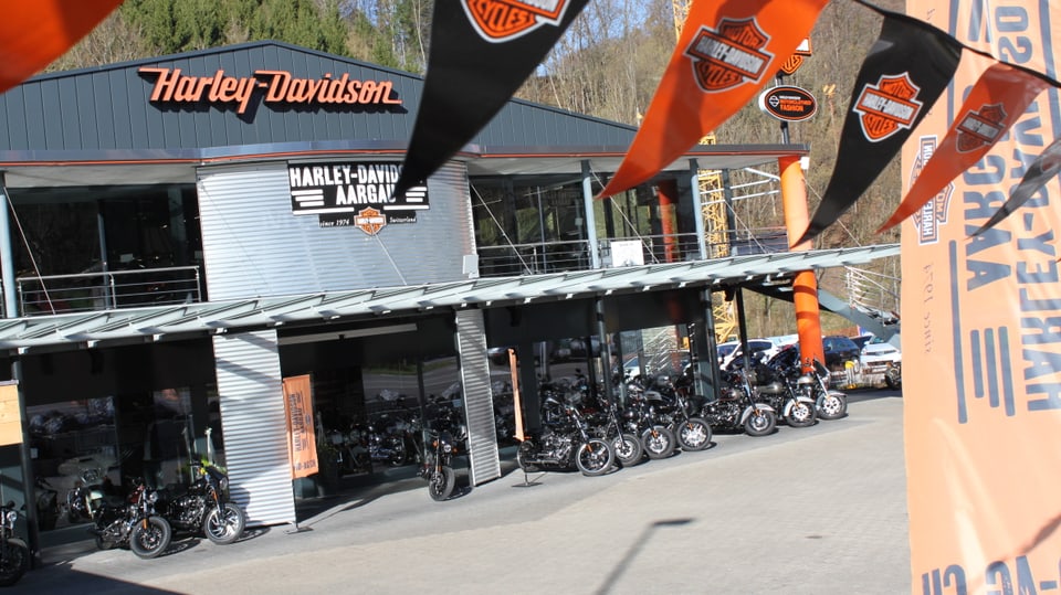 Der harley Laden in Densbüren - Aussenaufnahme. Im Vordergrund sind Harley-Flaggen zu sehen. 