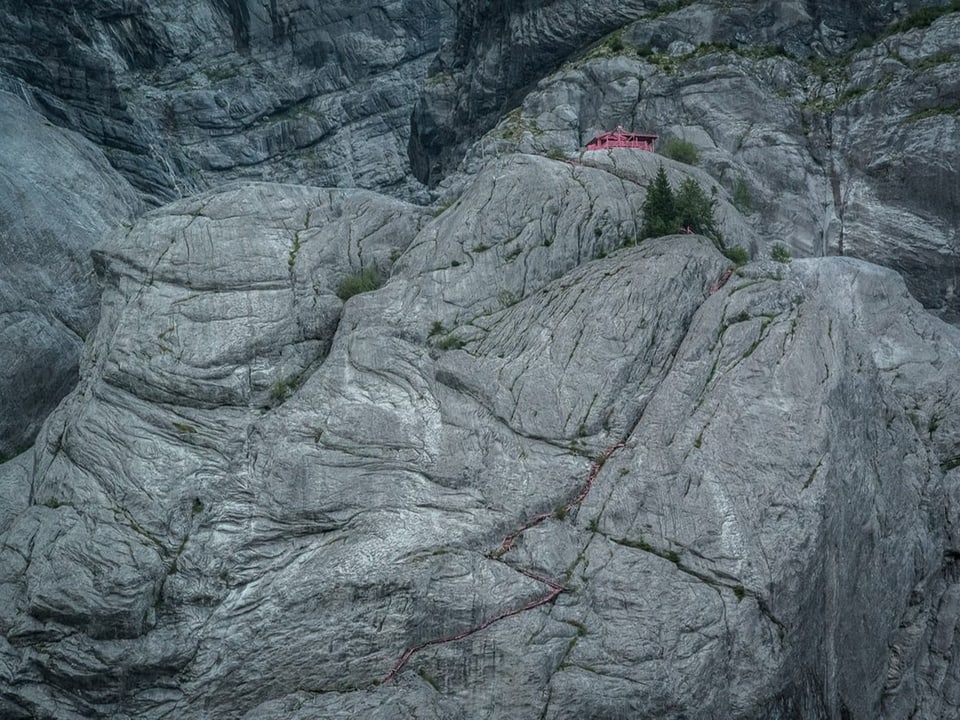 Kleines, pinkes Gebäude in einer Steinwand