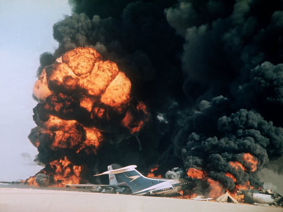 Rauch quillt über brennenden Flugzeugen in der Wüste auf