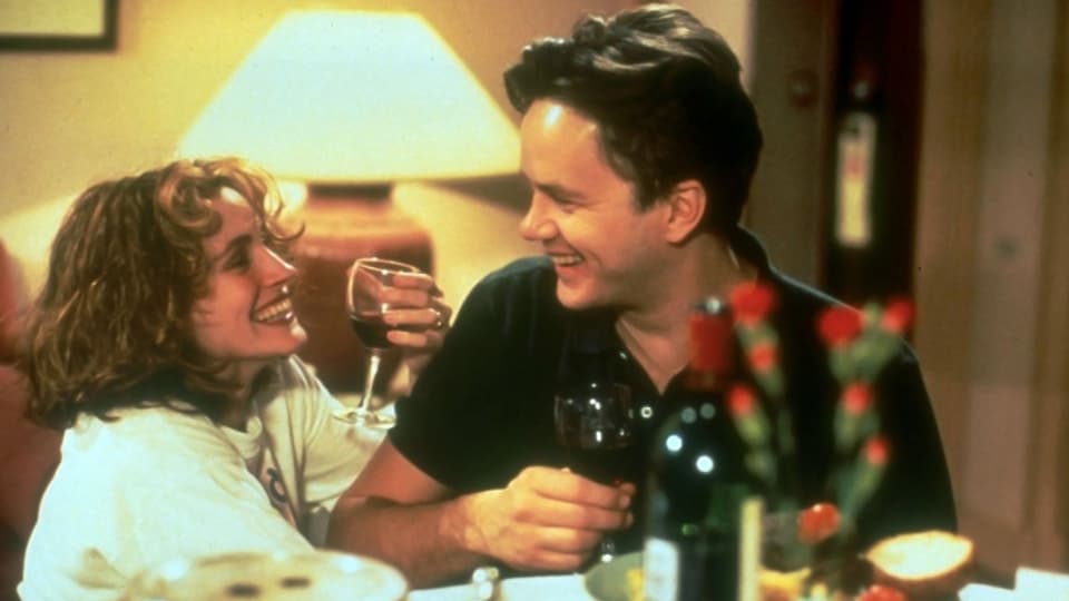 Eine Frau und ein Mann trinken Rotwein und lachen.