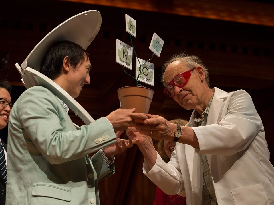 Nobelpreisträger Dudley Herschbach mit roter Brille übergibt lg-Nobelpreistrophäe an asiatischen Gewinner