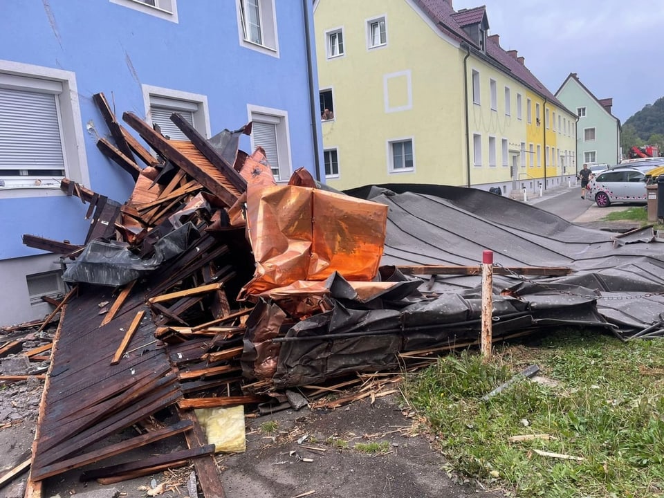 Broken parts of the roof lie near a house.