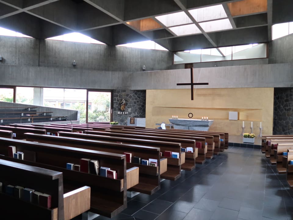 Blick in die Kirche mit Bänken und viel Licht.