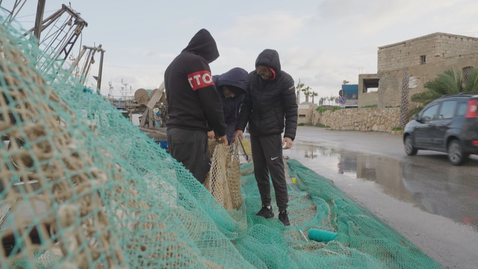Fishermen mend their nets in Lampedusa.