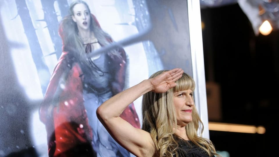 Eine Frau salutiert vor einem Filmplakat.