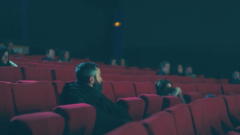 ein Mann sitzt im Kino und schaut sich um