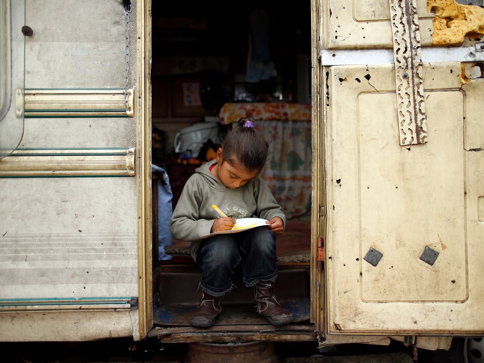 Ein Mädchen sitzt in einem Wohnwagen und zeichnet